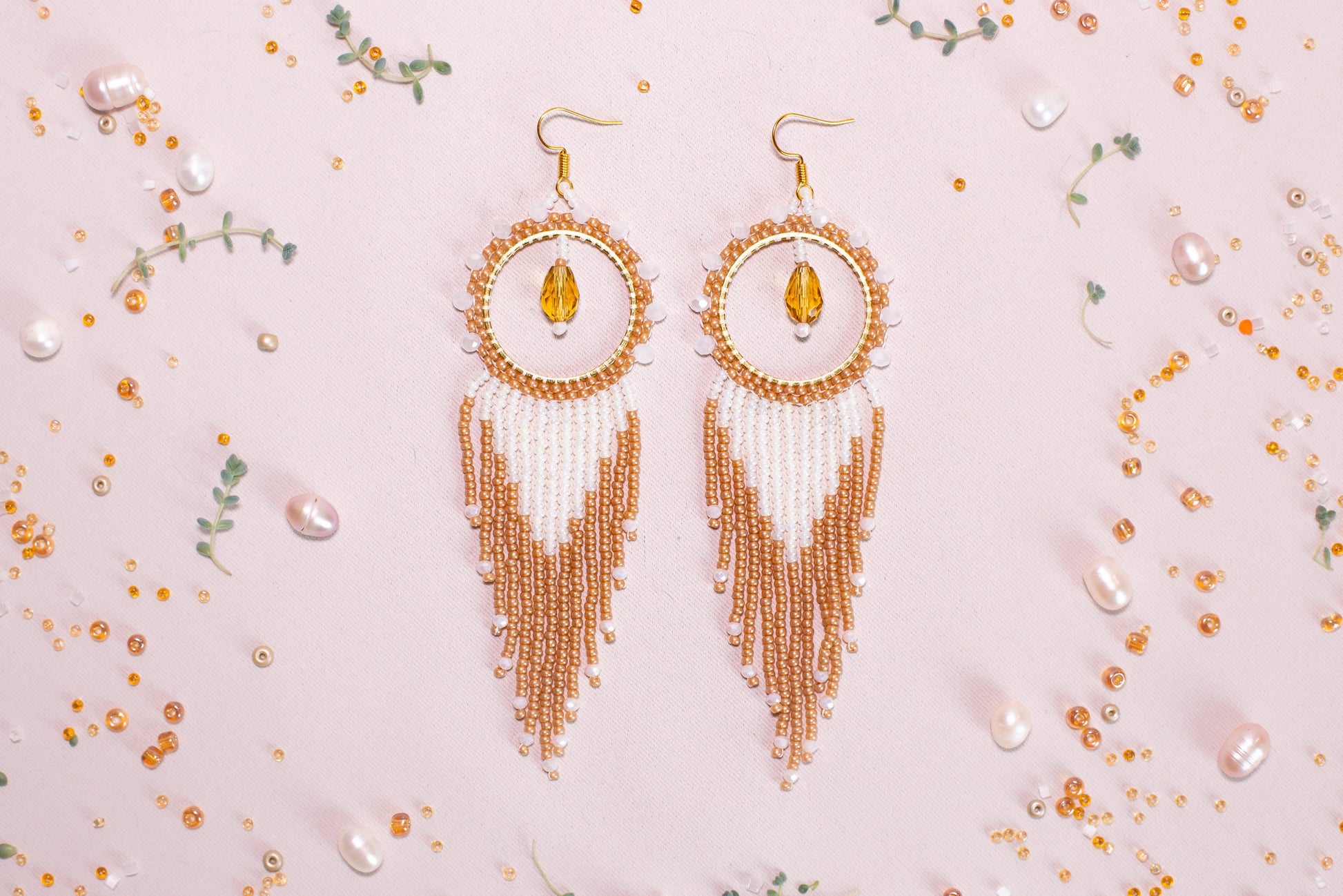 a pair of gold and white beaded earrings