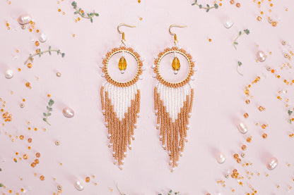 a pair of gold and white beaded earrings