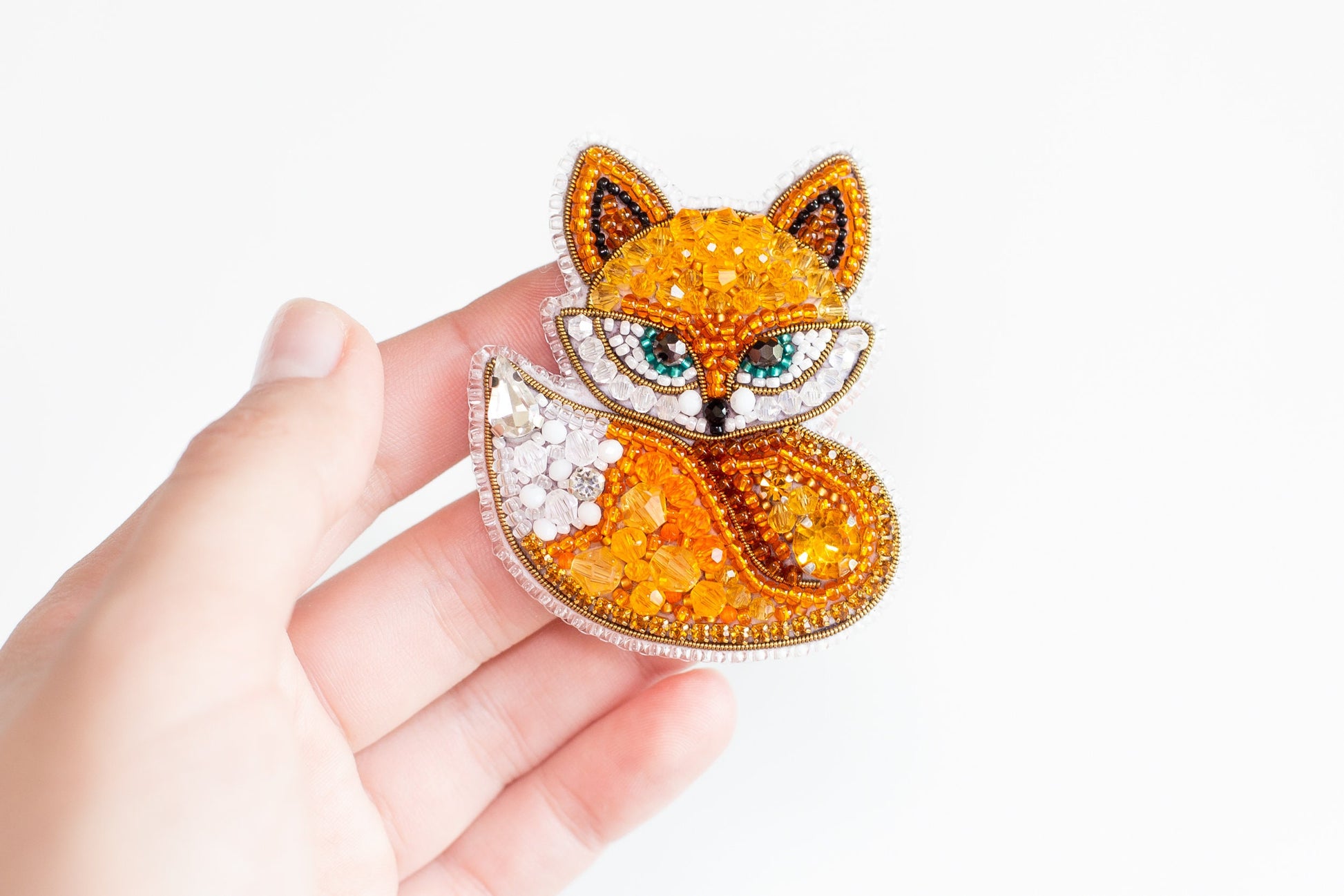 a hand holding a brooch with a fox on it