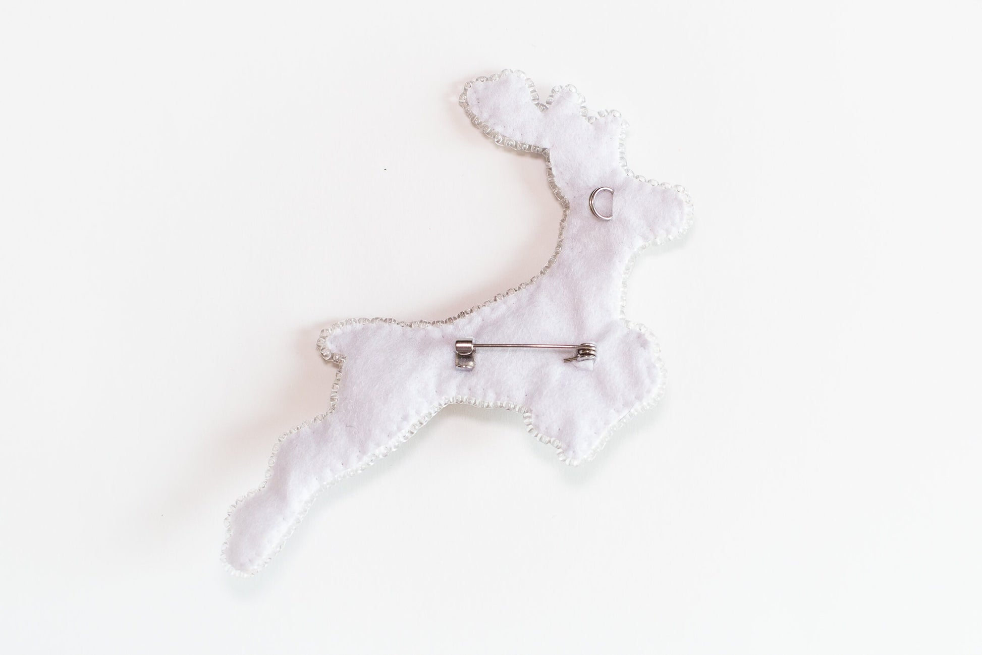 a white brooch with a pin in the shape of a dog