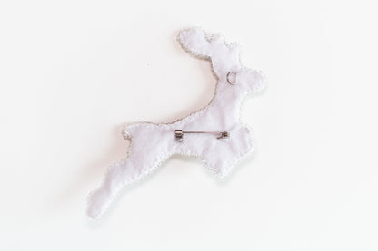 a white brooch with a pin in the shape of a dog