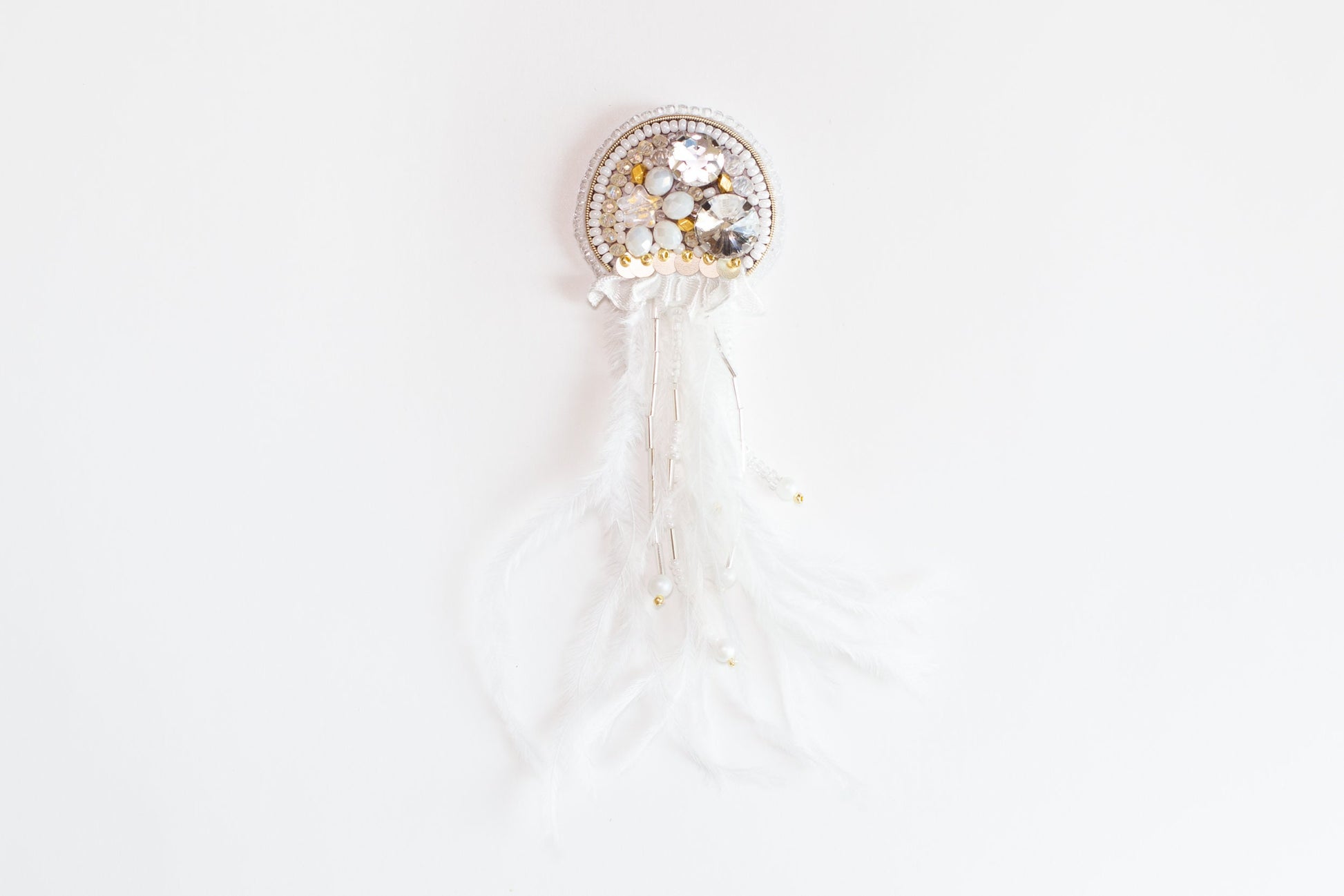 a white brooch with a white feather and beads