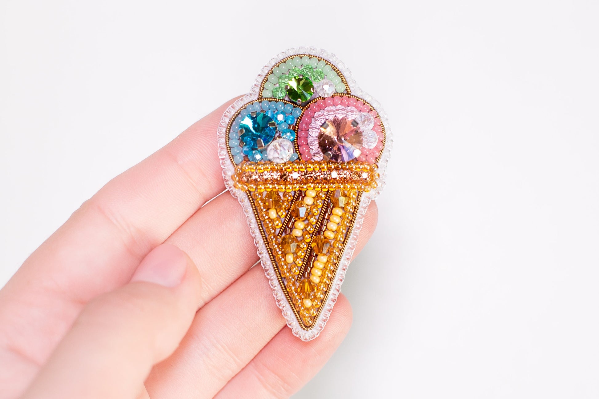 a hand holding a small ice cream pin