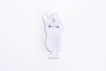 a white brooch with a white cat on it