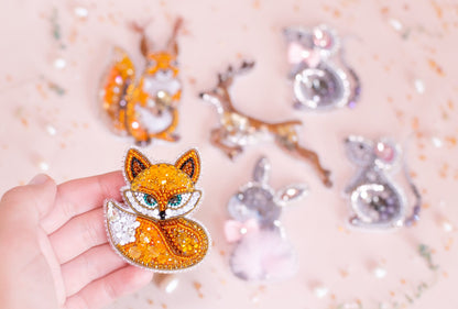 a hand is holding a brooch with a fox on it