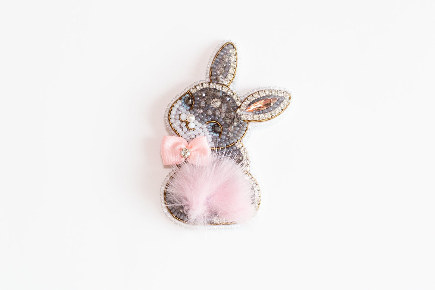 a rabbit shaped brooch with a pink bow