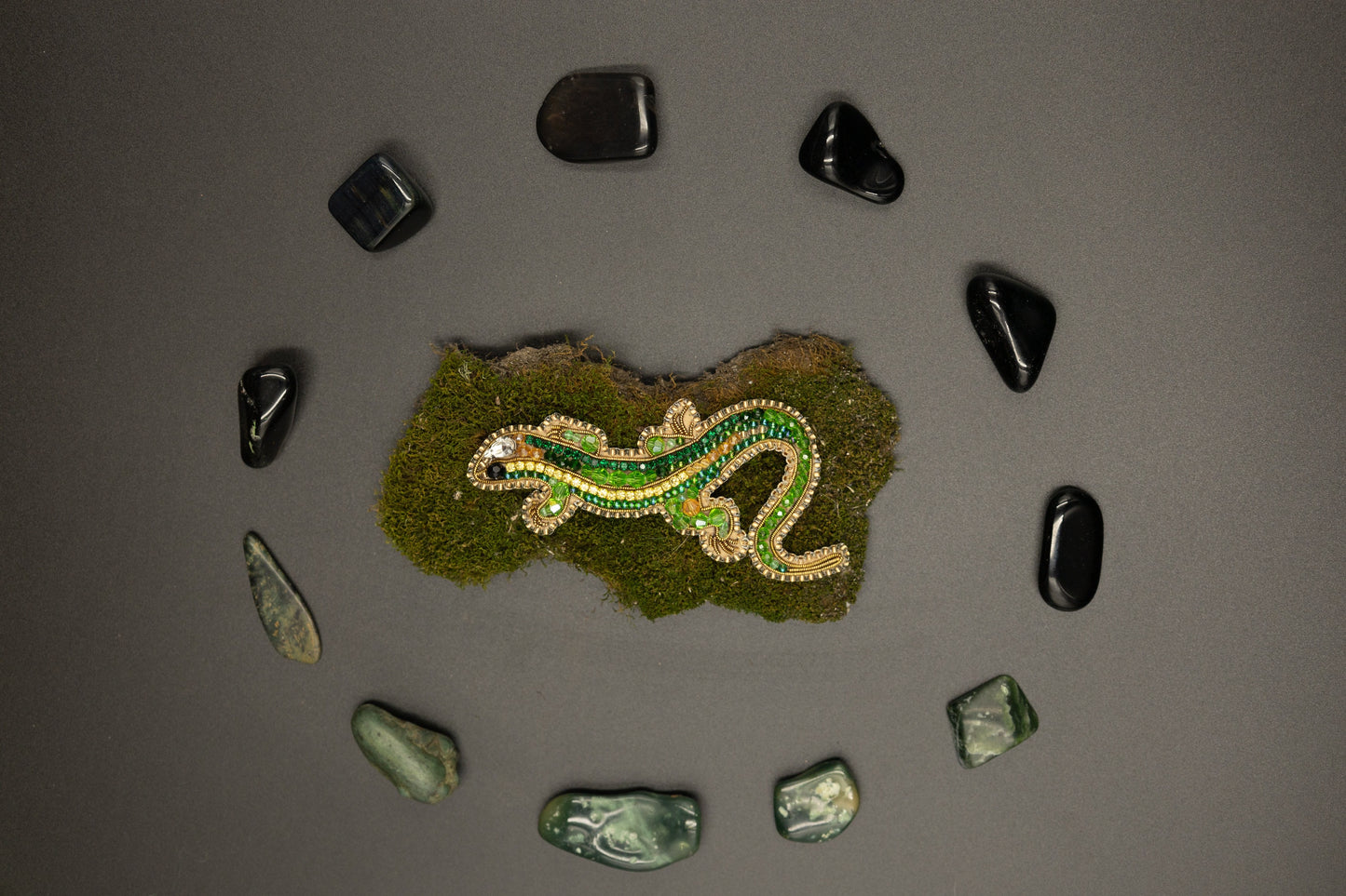 a green and yellow snake laying on top of a moss covered rock