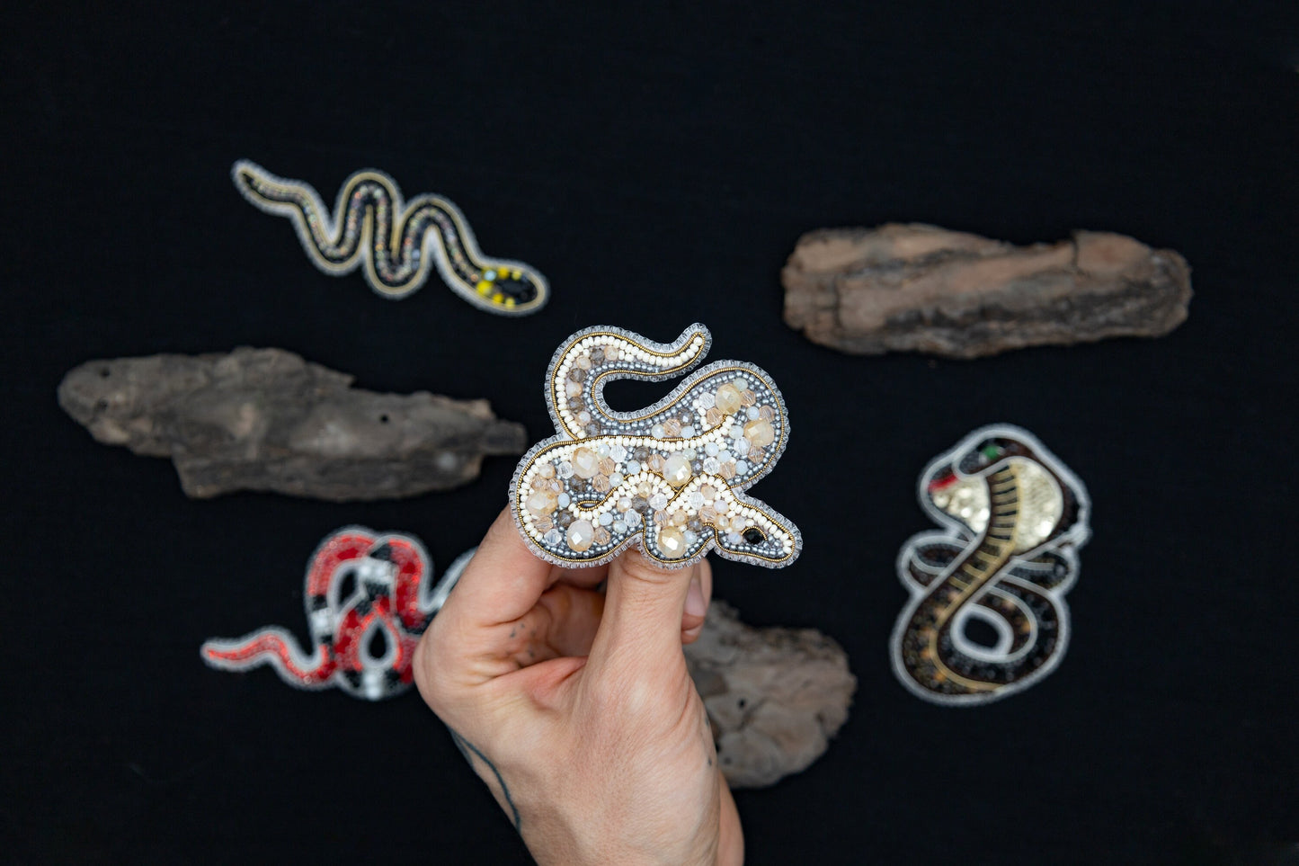 a person holding a piece of brooch with a snake on it