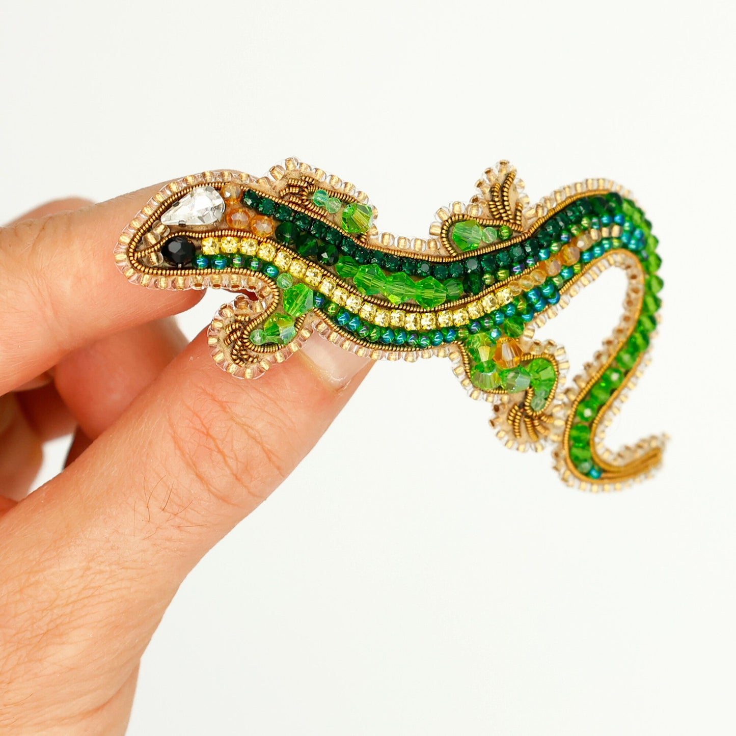 a hand holding a green and gold brooch